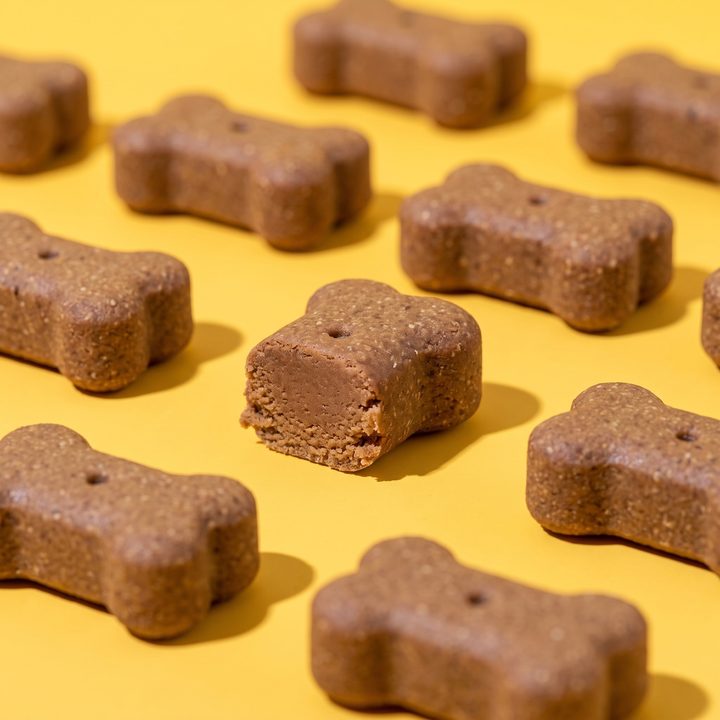 Chewdini soft bone-shaped chews on a yellow ground, one broken in half